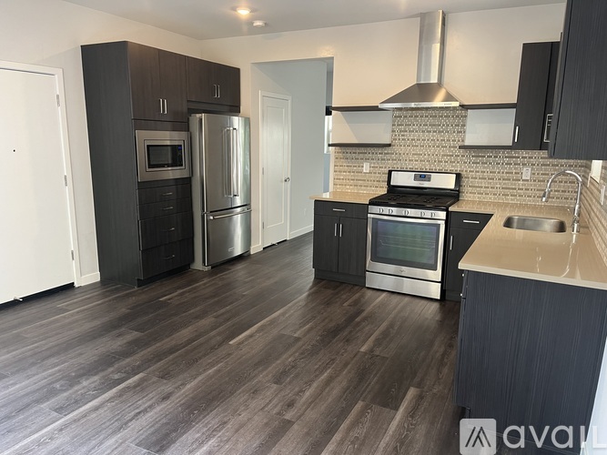 A kitchen with dark wood floors and stainless steel appliances.