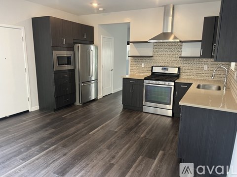 A kitchen with dark wood floors and stainless steel appliances.