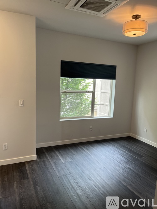 A room with a window and a wooden floor.
