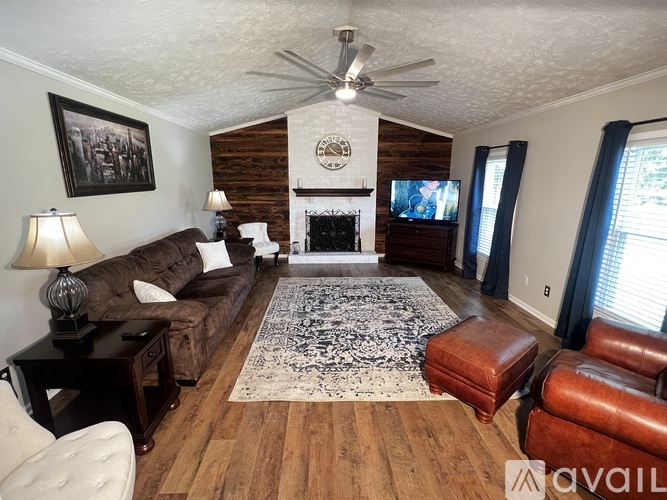 A living room with a fireplace and a rug in the middle.