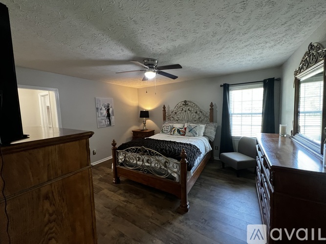 A bedroom with a bed, dresser, and window.