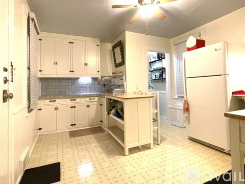 A kitchen with white cabinets and a white refrigerator.