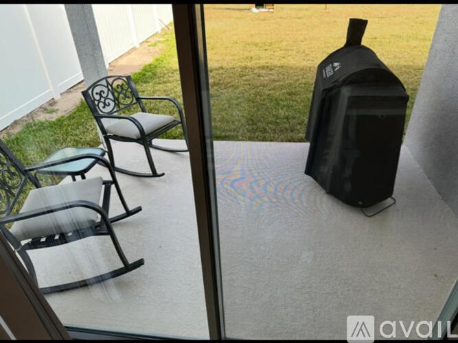 A black vacuum cleaner is on a patio with two chairs.