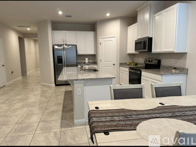 A kitchen with a refrigerator, microwave, oven, and sink.