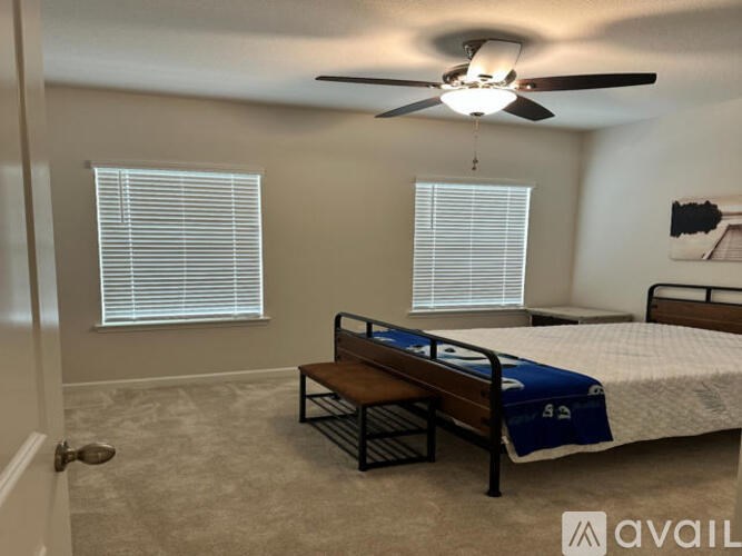 A bedroom with a bed, bench, and ceiling fan.
