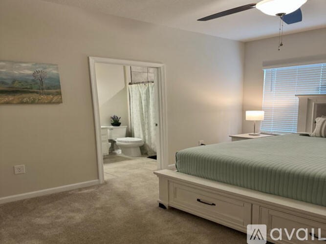 A bedroom with a bed, a toilet, and a painting on the wall.