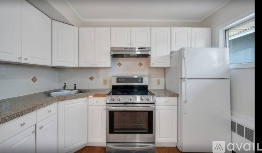 A kitchen with white cabinets and a stainless steel refrigerator.