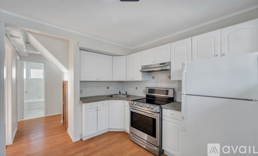 A kitchen with white cabinets and a white refrigerator.