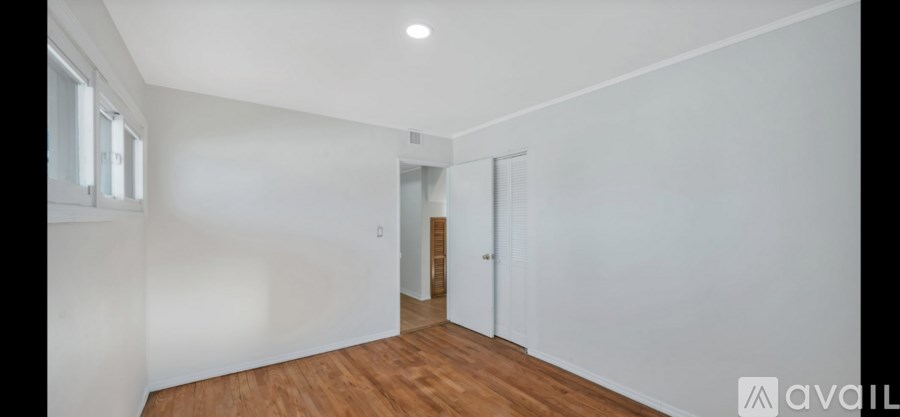 A room with wooden floors and white walls, with a door on the right side.
