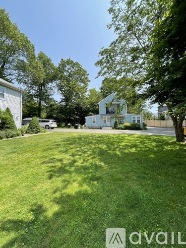 A well-maintained lawn with a house and trees in the background.