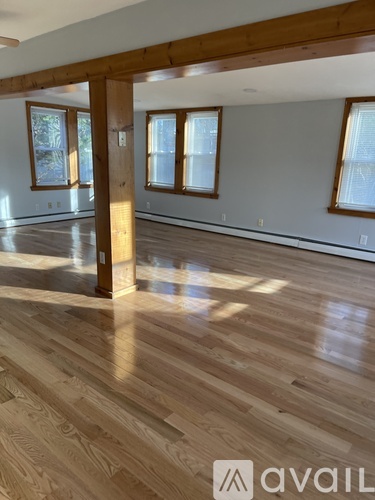 A spacious room with wooden floors and a large window.