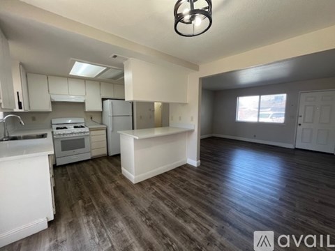 A kitchen with white cabinets and a wooden floor.