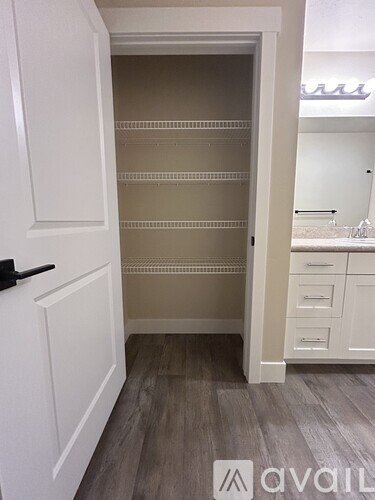 A white door with a black handle is open to a room with a white cabinet and drawers.
