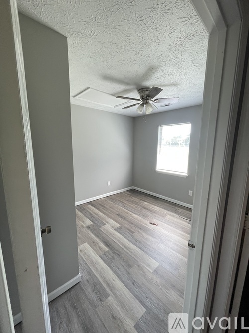 A room with a ceiling fan and wooden flooring.