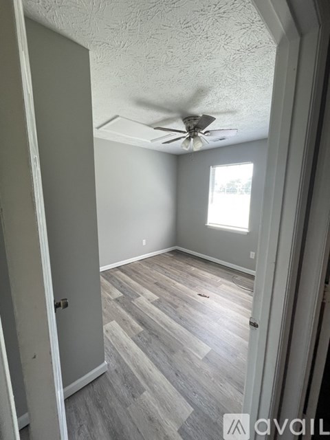 A room with a ceiling fan and wooden flooring.