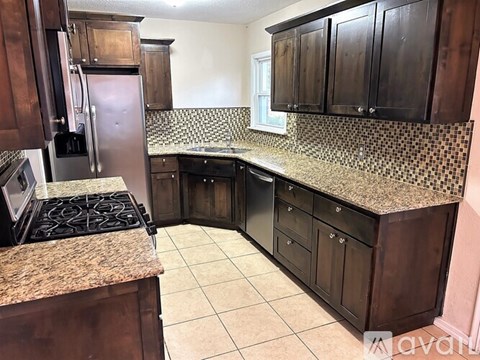 A kitchen with brown cabinets and a granite countertop.