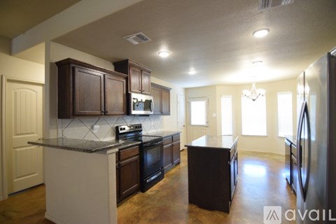 A kitchen with dark brown cabinets and black appliances.