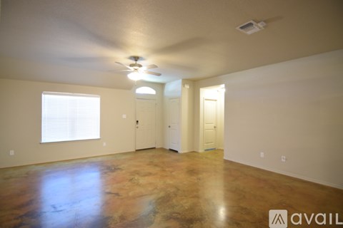 A room with a brown floor and a ceiling fan.