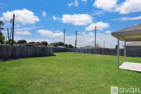 A backyard with a wooden fence and a covered patio area.