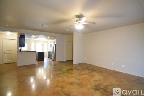 A spacious room with a ceiling fan and a brown floor.