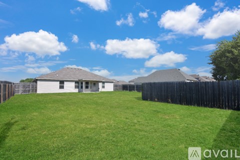 A white house with a grey roof is surrounded by a black fence.