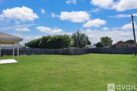 A backyard with a wooden fence and a clear blue sky.
