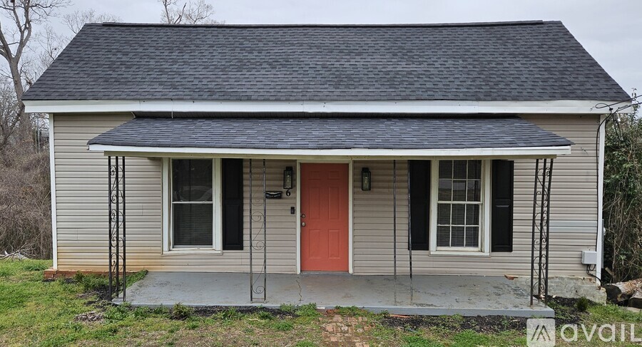 A small house with a red door and a porch.