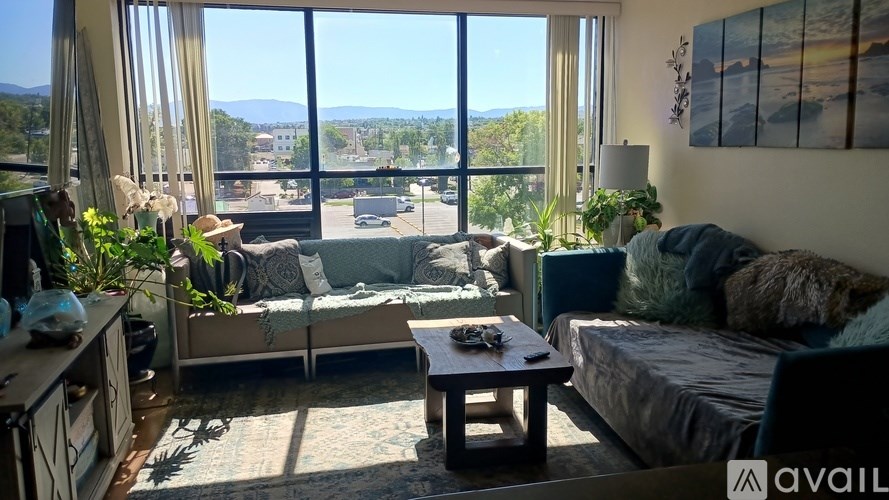 A living room with a couch, a table, and a view of the street outside.