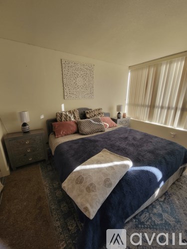 A bedroom with a bed, nightstand, and window.