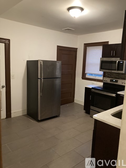 A kitchen with a black fridge and a window with blinds.