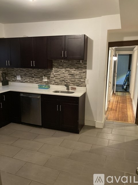 A kitchen with dark brown cabinets and a stone backsplash.