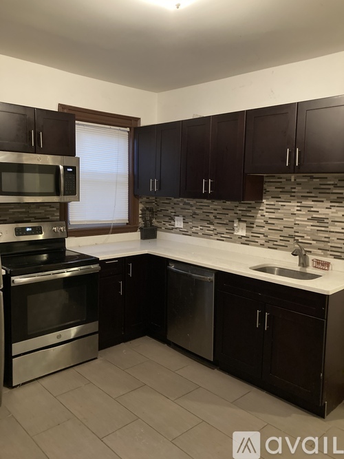 A kitchen with dark brown cabinets and a white countertop.