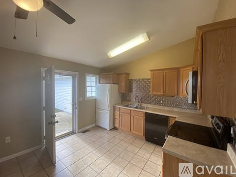A kitchen with wooden cabinets and a black fridge.