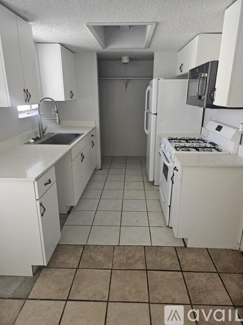 A kitchen with white cabinets and a tiled floor.