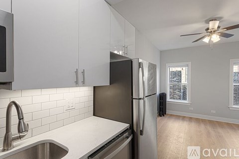 A kitchen with a black refrigerator and white cabinets.