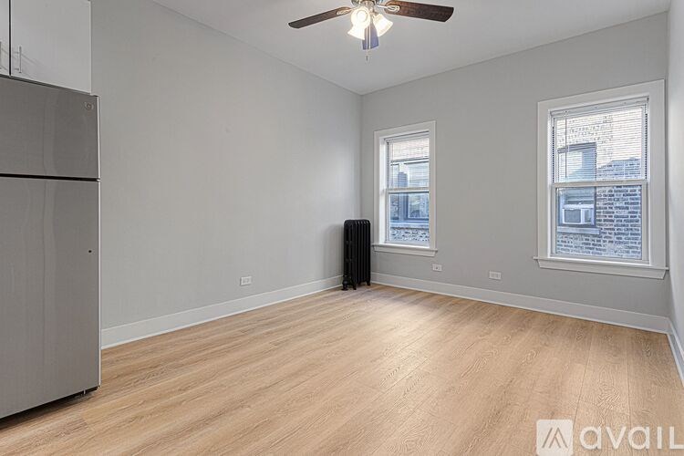 A room with a ceiling fan and two windows.