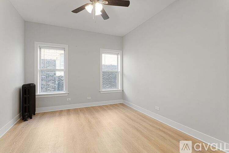 A room with a ceiling fan and two windows.