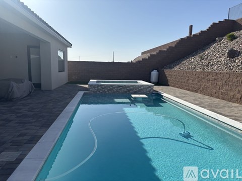 A small residential pool with a white wall and a stone staircase.