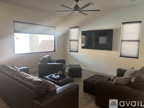 A living room with a brown leather couch and a ceiling fan.