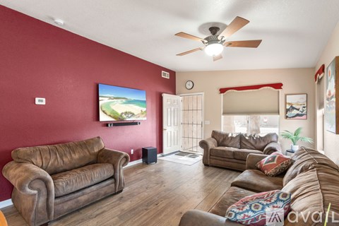 A living room with a brown leather couch and a ceiling fan.