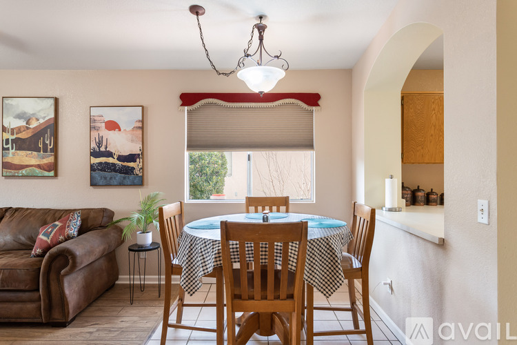 A dining room with a table set for four and a couch with a plant on it.