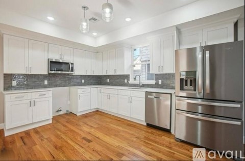 A kitchen with white cabinets and a wooden floor.