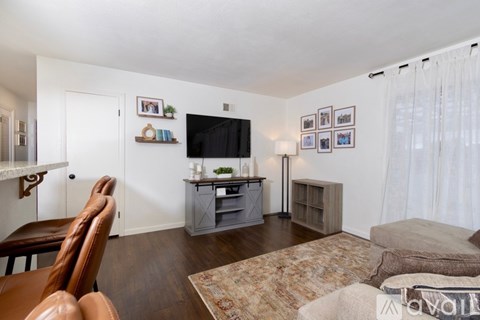 A living room with a brown leather chair and a television on a grey stand.