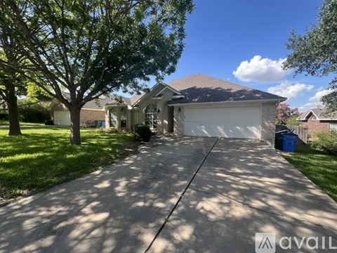 A house with a driveway and a tree in front of it.
