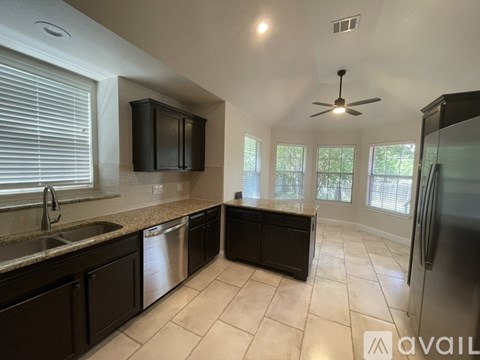 A kitchen with black cabinets and a stainless steel refrigerator.