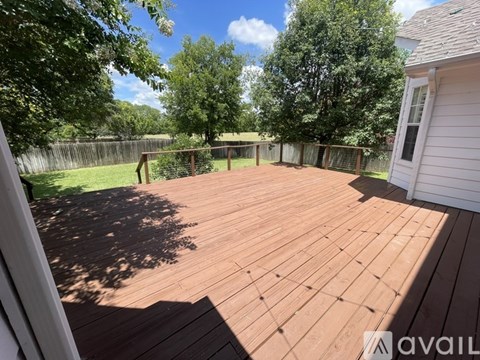 A wooden deck with a white house and trees in the background.