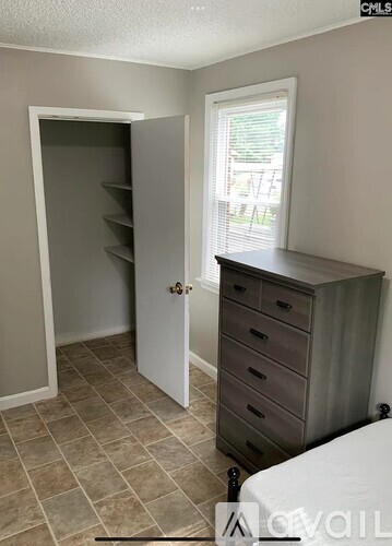 A room with a white door, a brown dresser, and a window with blinds.