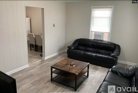A living room with a black leather couch and a wooden coffee table.