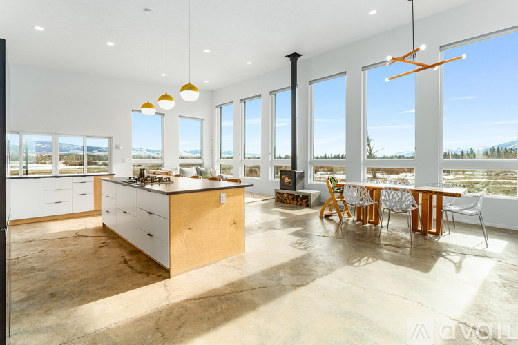 A modern kitchen with a large island and a dining table with chairs.