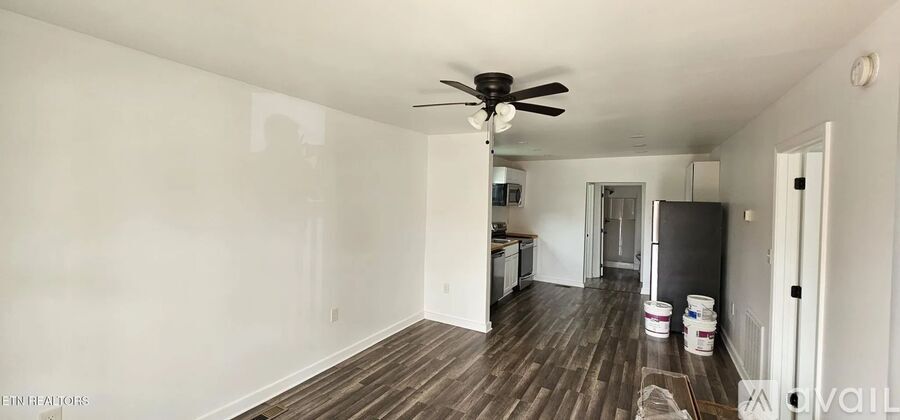 A room with a ceiling fan and wooden floors.